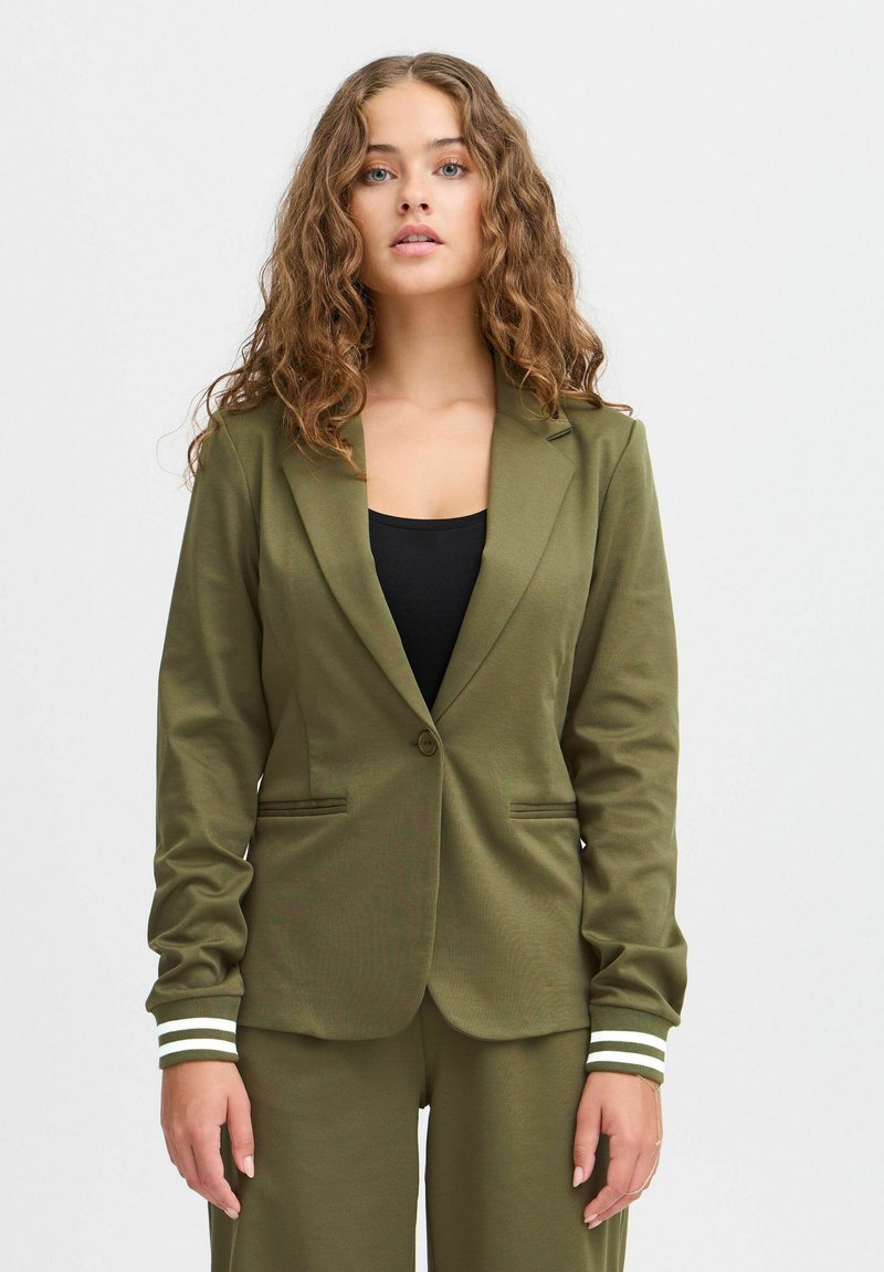 Olivově zelený blazer se strukturovaným límcem, jedním knoflíkovým zapínáním a manžetami se bílými pruhy. Hladká textura a přiléhavý střih.