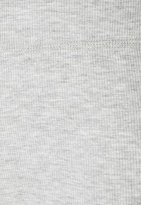 Gros plan sur un tissu côtelé gris clair avec une couture horizontale cousue au milieu.