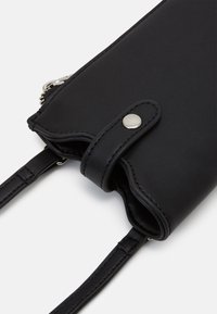 Clutch in vera pelle sintetica nera con chiusura zip, bottone a pressione e spallacci regolabili; texture liscia e design minimalista.
