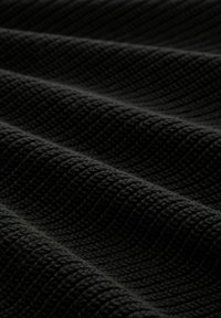 Musta kuvioitu kangas aaltoilevalla kuviolla, jossa on paksu kudottu ilme ja pehmeä, hieman koholla oleva pinta.