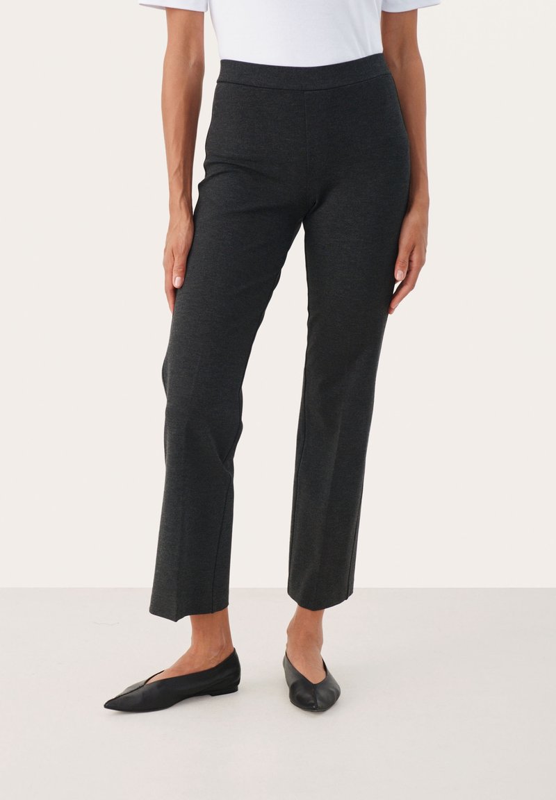 Pantalon extensible gris foncé avec une texture lisse, doté d'une large ceinture et d'une coupe droite. Associé à des ballerines noires au design simple.