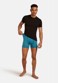 Black short-sleeve t-shirt paired with turquoise fitted boxer briefs, showcasing smooth fabric and a snug design.