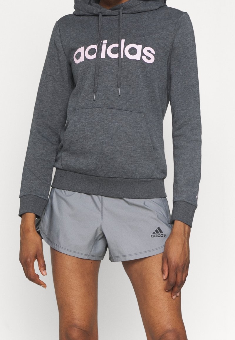 Szary hoodie z kapturem z różowym logo "adidas" i kieszenią z przodu, połączony z jasnoszarymi szortami sportowymi z czarnym logo.