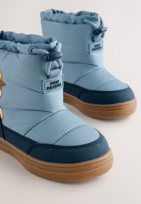 Hellblaue wasserdichte Stiefel mit einem gepolsterten Design, Marineakzenten und gummierter Sohle. Auf der Seite befindet sich eine Grafik einer Figur aus Paw Patrol.