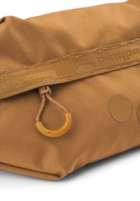 Brauner Stoffbeutel mit texturierter Oberfläche, ausgestattet mit einem dekorativen Riemen und einem runden orangefarbenen Clip-Akzent. Zwei runde silberne Hardware-Details sind sichtbar.