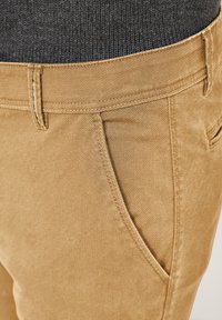 Beige cotton blend trousers with a smooth texture, featuring front pockets, belt loops, and a slim fit design.
