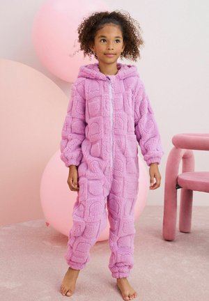 Combinaison en peluche rose avec un motif carré texturé, dotée d'une capuche et d'une fermeture éclair à l'avant. Matériau doux avec des poignets et des chevilles élastiqués.