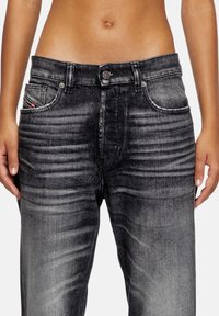Hoge taille, zwarte denim jeans met vervaagde textuur, vijf zakken en contrasterende stiksels. Voorzien van een knoopsluiting en subtiele merkdetails.