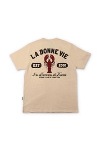 Lys beige bomull t-skjorte med korte ermer, med en stor rød hummergrafikk og svart tekst på baksiden, inkludert 'LA BONNE VIE' og 'EST 2001.'