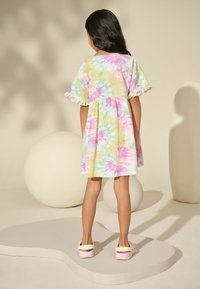 Dječja haljina od mekog materijala sa višebojnim tie-dye uzorkom u ružičastoj, žutoj i zelenoj boji, s volančićima na rukavima i opuštenim krojem.