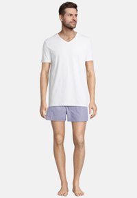 Biały bawełniany T-shirt w serek w połączeniu z jasnoniebieskimi szortami w białe paski. Szorty mają elastyczny pasek w talii i luźny krój.