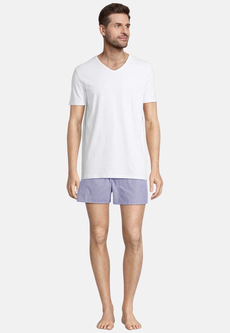Biały bawełniany T-shirt w serek w połączeniu z jasnoniebieskimi szortami w białe paski. Szorty mają elastyczny pasek w talii i luźny krój.