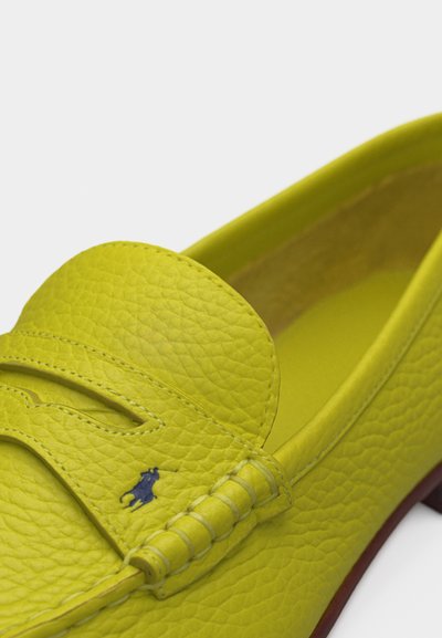 Κίτρινο δερμάτινο μοκασίνι με υφή από κόκκους, ραμμένη λεπτομέρεια λουριού και μικρό κεντημένο λογότυπο παίκτη πόλο κοντά στην πλευρά.