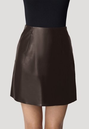 Jupe mini en cuir marron avec une texture lisse, en forme de A et une taille cintrée. Présente des coutures discrètes pour un look épuré.