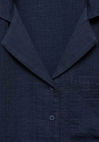 Dark navy button-up shirt with a textured fabric, featuring a notched collar, a chest pocket, and two buttons on the placket.