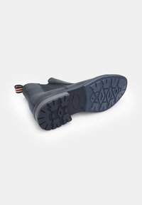 Botină neagră până la glezne cu talpă din cauciuc, având un model în carouri, părți elastice și un tab ce se trage cu dungi. Design din piele netedă și panou texturat.