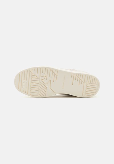 Semelle de sneaker beige clair avec caoutchouc texturé, motifs de bande de roulement visibles et marquage. Forme plate et arrondie, conçue pour l'adhérence et la flexibilité.
