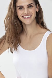 Top blanco sin mangas con un escote amplio y tirantes finos, hecho de una tela suave y ligera. El modelo sonríe, mostrando la textura natural de la piel.