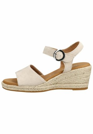 Beżowa sandałka na koturnie z paskiem na kostkę, czarną okrągłą klamrą, odkrytymi palcami i plecioną podeszwą z juty.