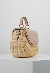 Tkany słomiany torebka z jasnobeżową skórzaną klapą. Ma zakrzywiony kształt, górną rączkę oraz złote akcenty metalowe. Teksturowane wykończenie.
