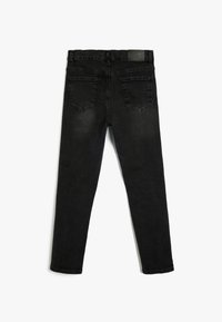 Pantalones vaqueros de mezclilla negra con ajuste slim, presentando una cinturilla, cinco bolsillos y un parche de logo cosido en la parte trasera. Textura suave y uniforme.