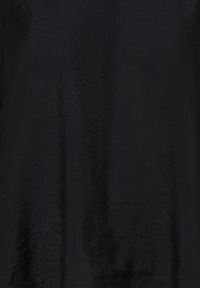 Černá tkanina s texturou, se subtilním vertikálním švem probíhajícím středem, vykazující mírné pomačkání a matný povrch.