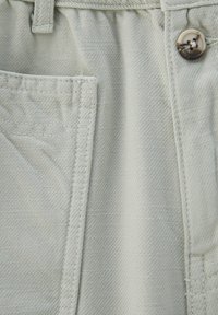 Světle šedé látkové šortky s kapsou a dekorativním knoflíkem, vyznačující se jemnou texturou a jemně šikmým vzorem.