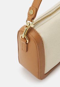 Bolso de lona beige con acentos de cuero color tostado, cremallera y herrajes dorados. Presenta una forma rectangular estructurada y detalles de costura.