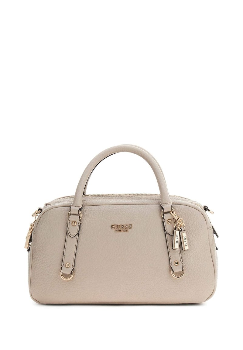 Beige leren Guess-handtas met een textuur, afgeronde handvatten, goudkleurige accenten, logo en twee bedel-tags die aan één handvat hangen.