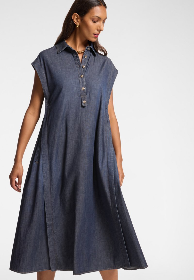 Abito in denim, con maniche corte a cappotto, bottoni sul davanti, colore blu scuro, vestibilità rilassata con spacchi laterali, morbida texture, lunghezza al ginocchio.