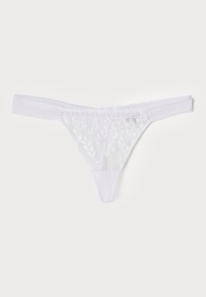 White lace thong featuring floral embroidery, soft elastic waistband, sheer material, and intricate detailing on the front and back.