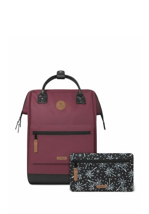 Zaino color marsala con accenti neri e un manico testurizzato; include una pochette nera con motivo, dotata di zip e etichetta con logo.