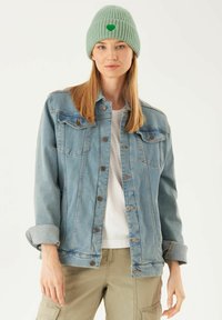 Leren jasje in lichtblauw met knoopsluiting en twee borstzakken, gecombineerd met een geribbelde mintgroene beanie met een hartembleem.