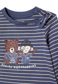 Gestreiftes blaues und beigefarbenes Langarmhemd mit Bären- und Affenmotiven sowie Druckknopfverschluss an der Schulter für ein einfaches Anziehen.