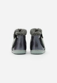Bottines en cuir gris foncé avec un doux bord en fausse fourrure grise, fermeture velcro et semelle vert clair. Texture lisse avec des accents minimaux.