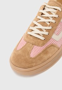 Adidaști din suede cu un superior bej și accente din corduroy roz, având șireturi crem și o talpă din cauciuc texturată. Branding simplu pe lateral.