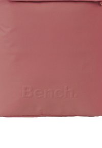 Sac rose texturé avec fermeture à rabat, présentant un logo en relief "Bench." sur le devant, fabriqué en tissu durable.