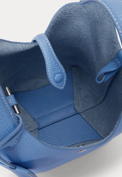 Εσωτερικό μπλε δερμάτινης τσάντας με μικρό λουράκι και κούμπωμα με κουμπί, που δείχνει υφή φόδρας και λεπτομέρειες ραφής.