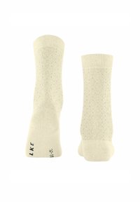 Helle beige Socken mit einem strukturierten Wabenmuster, gerippten Bündchen und gestempeltem Branding nahe der Ferse. Aus weichem Strickmaterial.