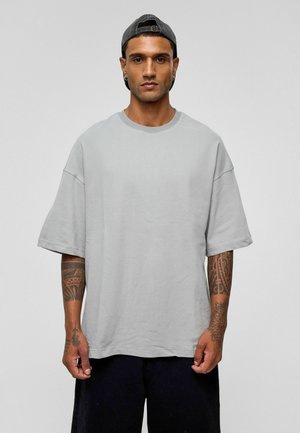Lichtgrijs oversized t-shirt met een ronde hals en korte mouwen, gemaakt van zachte stof. Heeft een strak ontwerp zonder zichtbare patronen.