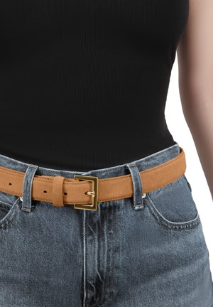 Brauner Wildledergürtel mit einer rechteckigen goldenen Schnalle, getragen über hoch-taillierten blauen Denimhosen. Glatte Textur und verstellbares Design mit Lochung.