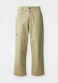 Khaki wide-leg trousers made of cotton, featuring a button closure, side pockets, and embroidered Nike logo in red on the side.