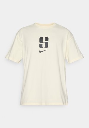 Krämfarvet kortærmet t-shirt lavet af bomuld, med et stort sort "S" og Nike-logo trykt på forsiden. Enkel design, afslappet pasform.