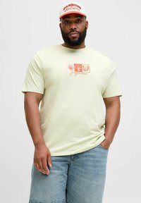 Lys gul bomulds T-shirt med et trykt logo i koralfarver over brystet, paired med blå denimshorts. Simpelt, afslappet fit.