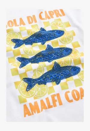 Una tela blanca presenta tres peces azules de cuentas, con un fondo a cuadros en amarillo y verde y texto naranja que dice “Isola di Capri Costa de Amalfi.”