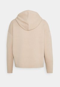 Beige Cropped-Hoodie mit großer Kapuze, überschnittenen Schultern und weichem Material. Einfaches Design ohne erkennbare Muster oder Verzierungen.