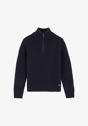 Tengerészkék kötött pulóver magas gallérral és fél cipzáros zárással. Jellemzője a bordázott mandzsetta és szegély, valamint egy kis logófolt az alján.