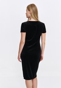 Czarna aksamitna sukienka, krótki rękaw, dopasowany krój, długość do kolan, okrągły dekolt, gładka tekstura, minimalistyczny design, brak widocznych wzorów lub akcentów.