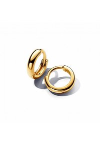 Goldene Creolen mit einer glatten, polierten Oberfläche. Das kreisförmige Design verfügt über einen nahtlosen Verschluss und reflektiert das Licht mit einer glänzenden Textur.