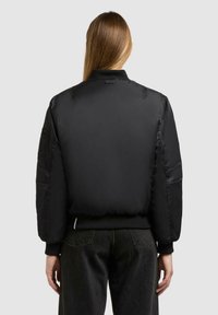Schwarze Bomberjacke aus glattem, glänzendem Stoff, mit gerippten Bündchen und taillierter Passform. Enthält seitliche Taschen und dezente Steppdetails.